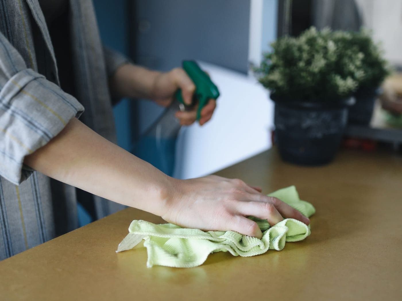 Main gantée essuyant une table au chiffon microfibre