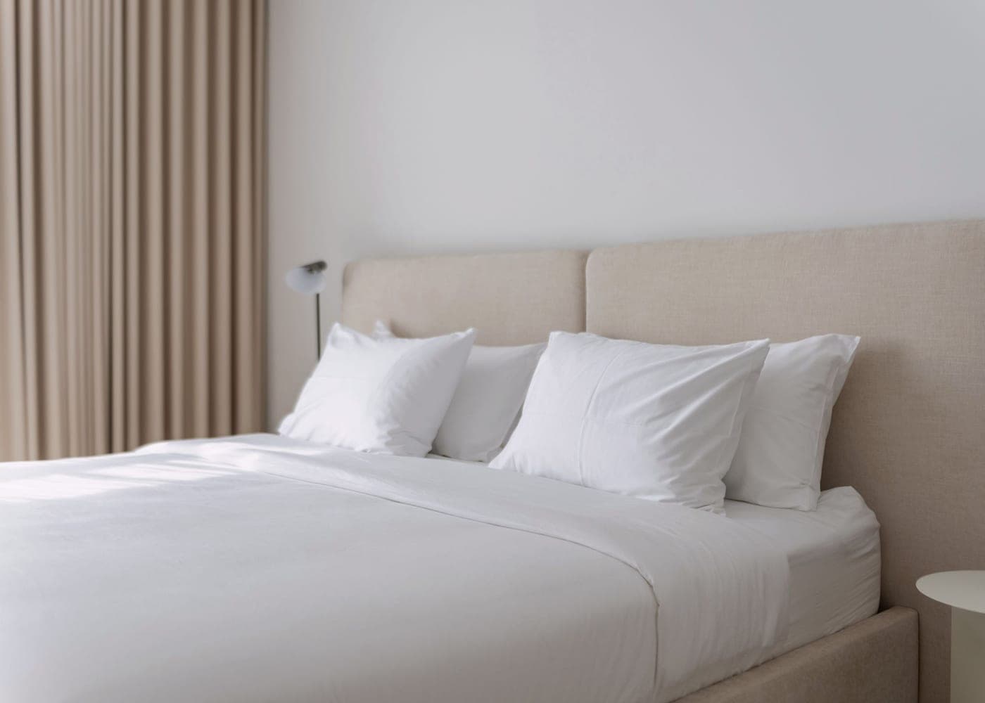 Lit double refait au linge blanc dans une chambre claire